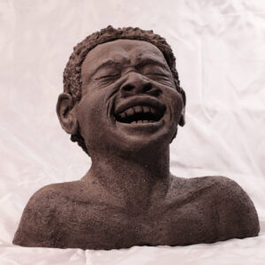 Schwarzafrikanischer Junge legt den Kopf nach hinten und lacht.